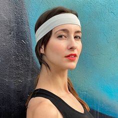 a woman with a headband standing in front of a blue wall