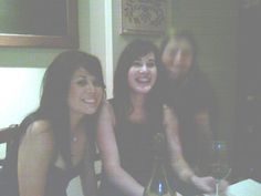 three women sitting at a table with wine bottles