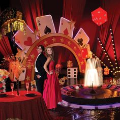 two people standing next to each other in front of a casino table with cards and dice