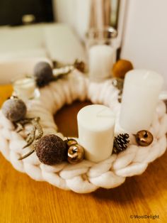 a crochet wreath with candles and other decorations on it sitting on a table