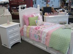 a bed room with a neatly made bed next to dressers and other furniture on display