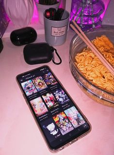 a cell phone sitting on top of a table next to bowls of noodles and chopsticks