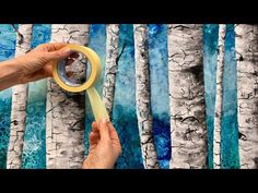 someone is holding a yellow tape in front of a painting of birch trees and blue water