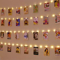 there are many pictures on the wall with lights strung from them and some string lights