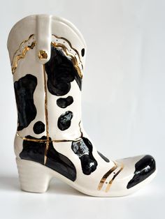 a pair of white and black cowboy boots with gold accents on the inside, sitting against a white background