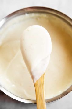 a wooden spoon with some white liquid in it and a wood stick sticking out of the bowl