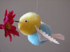 a stuffed bird hanging from a string next to a flower