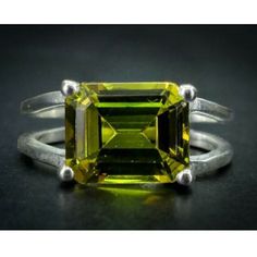 an emerald cut yellow sapphire ring on a black surface