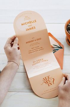 a person holding up a piece of paper next to a potted plant on a table