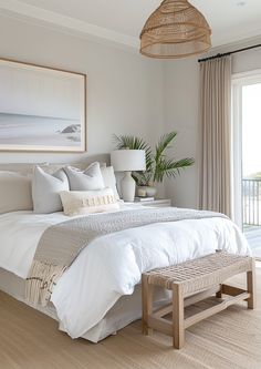 a bed with white linens and pillows in a bedroom next to a large window