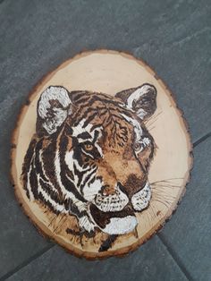 a tiger painted on a tree stump sitting on the ground with it's eyes closed