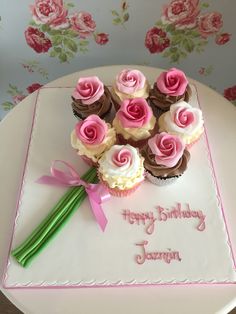 a birthday cake with cupcakes and flowers on it