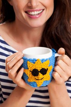 a woman holding a coffee cup with a smiling face on it