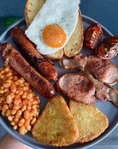 a plate with eggs, sausages, beans and toast on it next to other foods