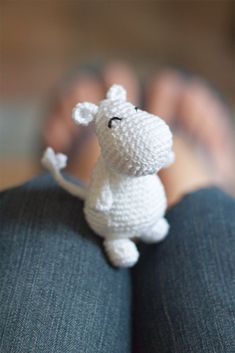 a small crocheted white dog sitting on top of a person's lap