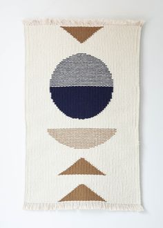 a woven wall hanging with different shapes and colors on the front, along with a white background