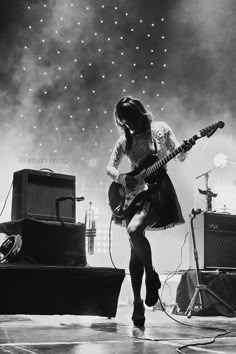 black and white photograph of woman playing guitar on stage