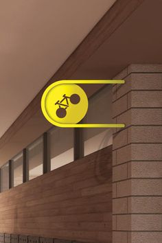 a yellow sign hanging from the side of a brick wall next to a building with two bicycles on it