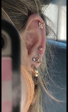 a woman's ear with three piercings on it