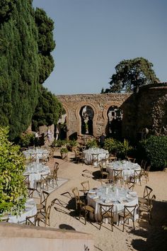 an outdoor dining area with tables and chairs set up for a formal function in the garden