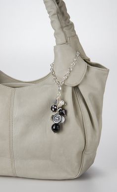 a white purse with a black and silver charm hanging from it's front pocket