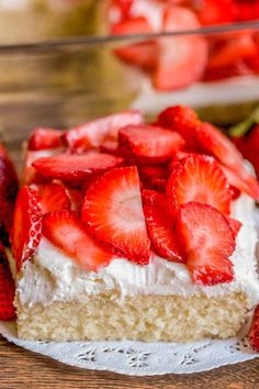 there is a piece of cake with strawberries on it and the rest of the cake in the background