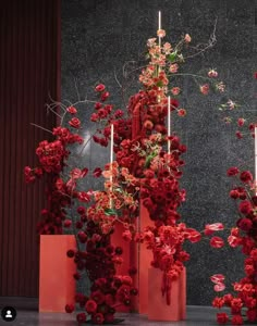 red vases with flowers and candles in front of a wall