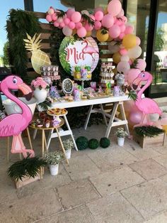 a table topped with pink flamingos and balloons