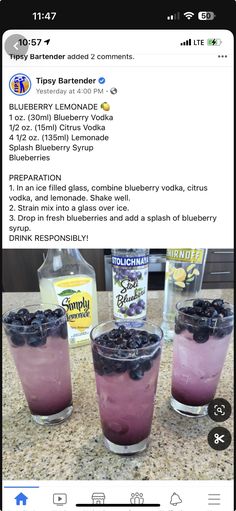 three glasses filled with blueberries on top of a counter next to an empty bottle