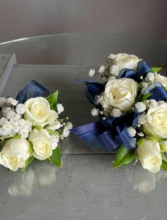 two bridal bouquets with white roses and baby's breath on a table