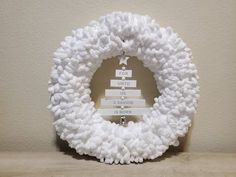 a white wreath is hanging on the wall with a name tag in front of it