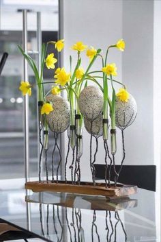 some yellow flowers are in vases on a glass table