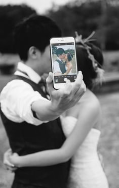 a bride and groom taking a photo with their cell phone in front of the camera