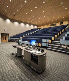 an empty auditorium with rows of seats and computers on the desk in front of them