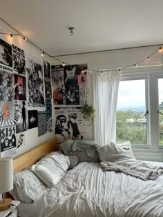 an unmade bed in a bedroom with posters on the wall and lights strung from the ceiling