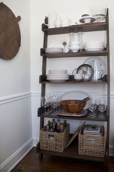 a wooden shelf with dishes and glasses on it next to a wall mounted plate rack