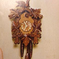 a wooden clock hanging on the wall with an eagle and leaves decoration around it's face