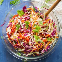 a glass bowl filled with coleslaw and carrots on top of a blue table