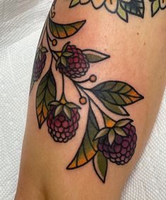 a woman's leg with flowers and berries on it