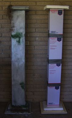 two tall white pedestals sitting in front of a brick wall