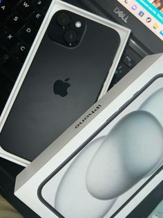 an apple phone sitting in front of a laptop computer with its box open on the desk