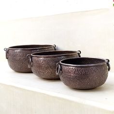 three metal bowls are sitting on a ledge