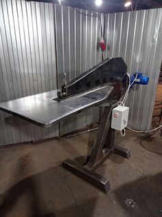 a metal work bench in front of a wall with corrugated walls behind it and an electrical device hooked up to the table