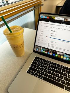 an open laptop computer sitting on top of a table next to a cup of coffee