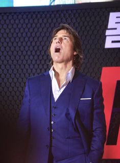 a man in a blue suit and white shirt is making a face with his mouth open