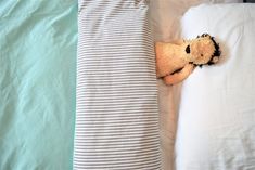 a teddy bear laying on top of a bed next to a white pillow and blanket