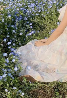 a woman is sitting in the middle of blue flowers