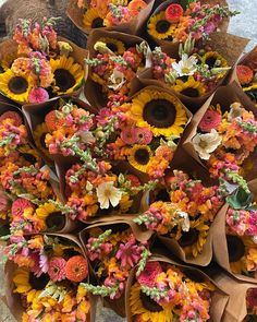 a bunch of sunflowers and other flowers are arranged on brown paper bags with green stems