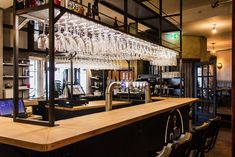 a bar with lots of wine glasses hanging from the ceiling