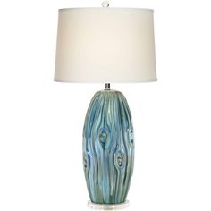 a table lamp with a white shade on it and a blue swirl design vase in the center